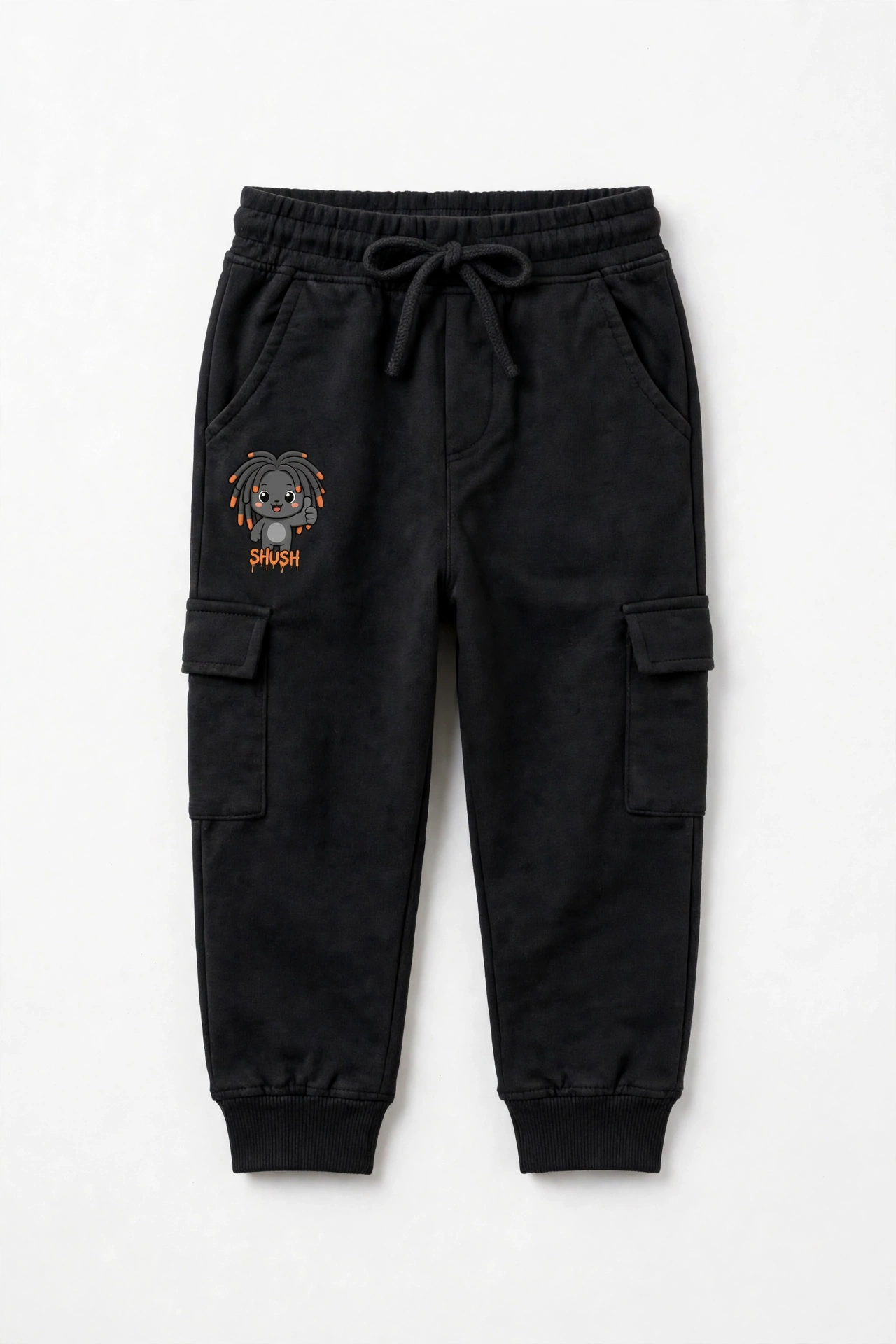 SHUSH kids cargo joggers in Black — the laughing light-gray friend on the leg, Magic Out of the Blue underneath, a tiny SHUSH label at the hem