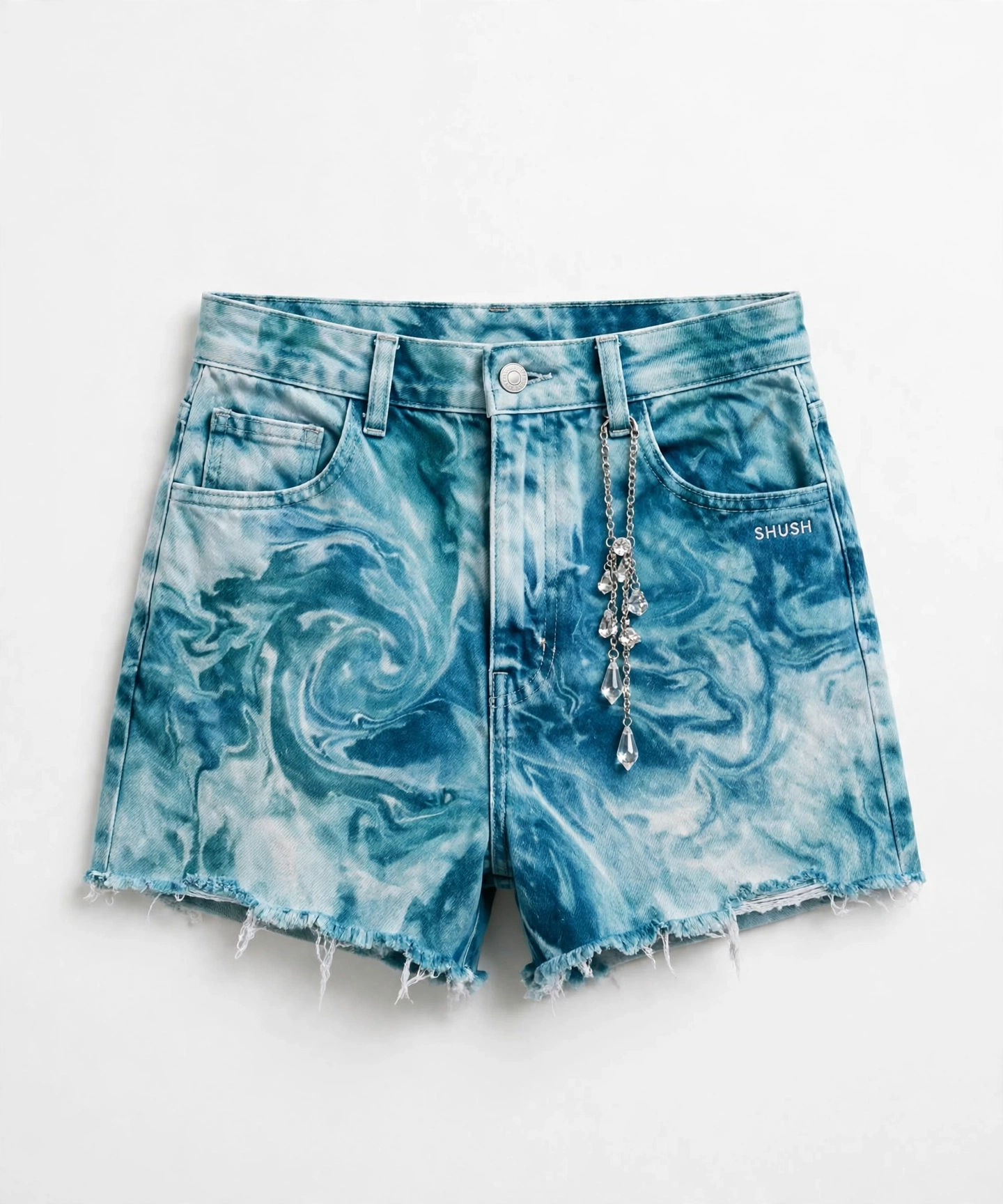 Women\u2019s tie-dye denim cutoff shorts in a teal and white aqua marble wash with a silver chain of clear crystal gem drops and a small white SHUSH by the front pocket